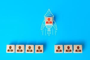 A human figurine flies out of a row of colleagues on a drawn doodle rocket. Promotion at work, appointment to team leader. Initiative and aspiration. Impressive success, a business career accelerator. photo