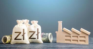 Polish zloty money bags and industrial factory. Subsidies support for businesses. Investments in production and energy industry. Budget forming economy subjects. Concession auction tender. photo