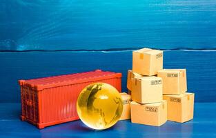 Planet Earth globe near a cargo container and boxes. World trade in goods. Economic ties. Production chains and product distribution. Freight shipping delivery. Transportation and transfer photo