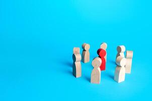 Red figurine of a man surrounded by people. Leader and significant person, important. Uniting around a team of people. Cooperation and teamwork. Attracting attention, public speaking. Enlist support. photo