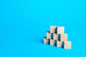 Wooden blocks pyramid on a blue background. Slide for presentation. Copy space, place for text. Steps. Minimalism. Simple shapes geometry. photo