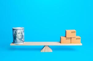 Money bundle of dollars and boxes on scales. Trade balance and purchasing power. Commerce and business. Minimum wage and living wage. Import and export duties, profit from sale of value added goods. photo