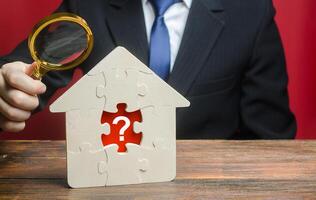 A man examines a house with a missing puzzle inside. Property valuation. Finding problems and structural hidden defects. Checking for compliance with the parameters criteria. Solving housing problems photo