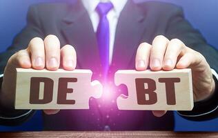 Man breaks puzzles with word Debts. Debt restructuring. Financial distress. Refinancing loan workouts. Challenging the legality of debt collection and writing off penalties. Deferment of payment photo