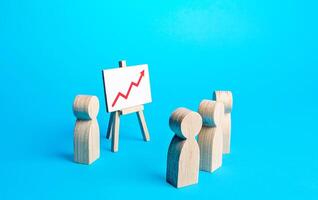 People in the meeting are looking at the presentation of the results of the easels with a red arrow pointing up. Statistics and data. Business development. Marketing strategy. Economic forecasting. photo