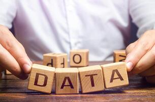 The man tries to pick up blocks with the word Data. Digital data integrity and security vulnerability concept. Fault tolerance, backup. Financial data leakage, password draining. Increased reliability photo