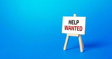 Easel with the words Help Wanted. Call for help, volunteering. Search and recruitment of new employees for work. Providing support. Drawing attention to a social problem. Advertising. Staff expansion photo