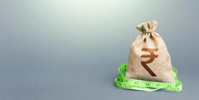 Indian rupee money bag and measuring tape meter. Analysis of economic situation. Formation and optimization of the budget, savings. Declaration of income, illegal enrichment. Assessment of capital. photo
