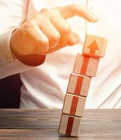 A man knocks down a tower of blocks with an up arrow. End of career, destruction of progress and achievements. Sabotage. Eliminate the phenomenon, prevent further growth. Disruption business processes photo