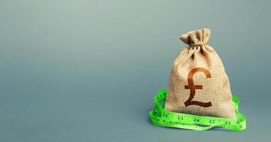 British pound sterling money bag and measuring tape meter. Analysis of economic situation. Formation and optimization of the budget, savings. Assessment of capital. Declaration of income, illegal. photo