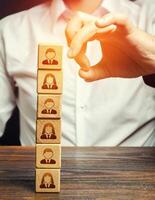 Man knocks down a tower of blocks with employees. Mass layoffs, closing a business company. Dismissal workers. Elimination of competitors, repression. Poor leadership. Disbandment of team collective. photo