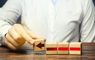 Man builds an red arrow from blocks. Business development, growth process concept. Progress and movement forward. Career promotion, improving skills. Business building and expansion. Goal achievement. photo