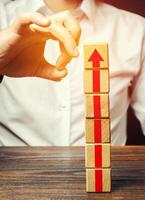 A man knocks down a tower of blocks with an arrow up. End of career, stop the progress and achievements. Eliminate the phenomenon, prevent further growth. Disruption business processes. Sabotage. photo