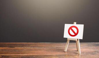 Easel with the prohibition sign NO. Restricted area. Restrictions and sanctions. Inaccessibility. Blocking. Out of stock. Ban and Embargo. Failed strategy. Denying entry, stopping action processes. photo