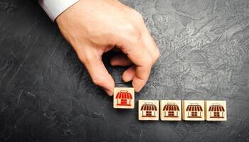 Man Adding a block with a store icon to others. Franchise commercial concession concept. Investing in asuccessful business model. Building a business empire. Expansion and competitive growth photo