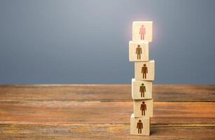 Red leader on top of a tower of people. Leadership skills. Teamwork, cooperation and collaboration. Management of effective and powerful team. Risk management and even distribution of work load. photo