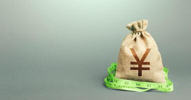 Yen Yuan money bag and measuring tape meter. Analysis of the economic situation. Assessment of capital. Declaration of income, illegal enrichment. Formation and optimization of the budget, savings. photo