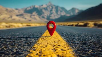 Red location pin marker stands out against yellow road line on empty desert highway, with mountain silhouettes and vibrant blue sky creating cinematic travel scene. mountains photo