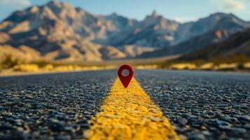 Red location pin marker stands out against yellow road line on empty desert highway, with mountain silhouettes and vibrant blue sky creating cinematic travel scene. navigation photo