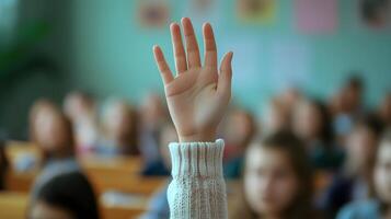 White-sleeved hand raises in classroom environment, representing participation and volunteering against blurred background with warm lighting and educational context. active photo
