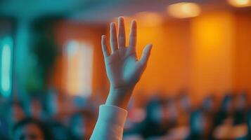 White-sleeved hand raises in classroom environment, representing participation and volunteering against blurred background with warm lighting and educational context. eager photo