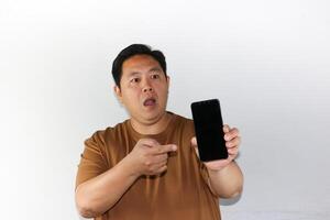 Wow expression A man while showing his blank screen of smartphone over isolated white. photo
