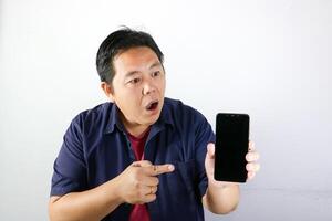 Shocked, surprised and wow expression of handsome Man using his smartphone over isolated white background. photo