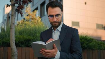 Thoughtful pensive man Caucasian businessman business coach in city write notes in notebook university professor writer thinking writing ideas at paper notepad smiling prepare for class lesson outside photo