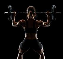 Strong woman lifting barbell in gym at night highlighting fitness and determination photo
