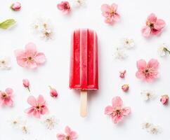 Colorful popsicle surrounded by pink flowers on a white background in a bright indoor setting photo