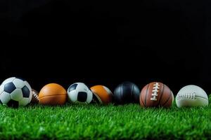 Various sports balls arranged on green grass with a dark background highlighting their different designs and materials photo