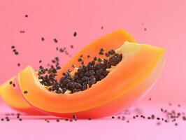 Fresh papaya slice with seeds on a vibrant pink background showcasing natural textures and colors photo