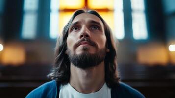 Man praying in a serene church setting with stained glass windows illuminated by sunlight photo