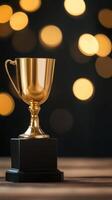 Shiny gold trophy on a black pedestal surrounded by blurred golden lights in a celebratory atmosphere photo