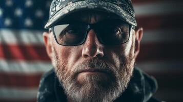 Veteran wearing sunglasses stands in front of an American flag during a solemn moment of reflection photo