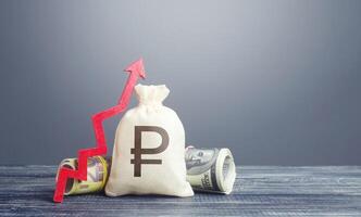 Russian ruble money bag and red arrow up. Influx of investment and capital, increase of wealth. Economic recovery, optimistic forecast of economic rise. Market stability. Rising inflation. photo
