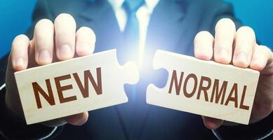 Man collects word New Normal from puzzles. Adaptation of business to post-crisis working conditions, implementation of new rules, search for online sales platforms for products. Opportunities photo