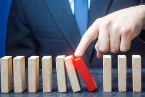 Businessman starts the process of falling dominoes. Correction of errors malfunctions. Implementation of plans. Starting work after stopping. Continuation working, obstacle avoidance. Maintainability. photo
