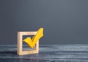 Yellow voting tick in a checkbox. Democratic institutions, vote on democratic elections, referendum. Opinion Poll. Make right choice. Confirmation, passing the test. Verification. Law implementation photo