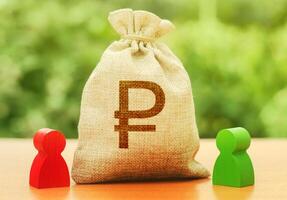 Russian ruble money bag and two people figures. Business Investment and lending, leasing. Dispute solution between two businessmen. Division of property. Business relationship. Trade agreement deal photo