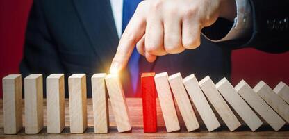 Businessman restarts the process of falling dominoes. Start work after stopping. Continuation of working, obstacle avoidance. maintainability. After the weekend. Correction of errors and malfunctions. photo