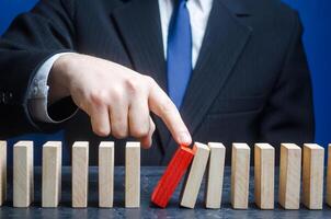 Businessman starts the process of falling dominoes. Starting work after stopping. Continuation of working, obstacle avoidance. maintainability. Correction of errors and malfunctions photo