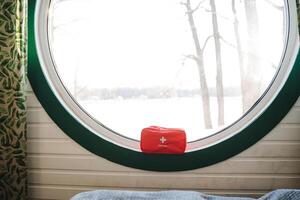 Experience the captivating beauty of a charming circular window that offers a stunning scenic view, complemented by vibrant red outdoor gear for an adventurous touch photo