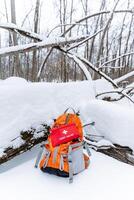 A backpack that contains a wellstocked first aid kit is currently sitting quietly in the thick blanket of fresh, white snow, waiting for someone to come across it in the winter wilderness photo