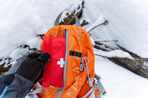 A determined individual stands in thick snow, confidently holding a reliable backpack with a stocked first aid kit, ready for any emergencies during their winter adventure photo