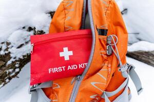 An orangecolored backpack that contains a wellstocked first aid kit inside it for emergencies while engaging in outdoor activities or adventures like hiking or rock climbing photo