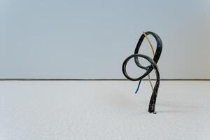 A broken wire is elegantly showcased on a pristine white surface, intricately emphasizing its detailed structure and vivid contrasting colors that stand out against the clean background photo