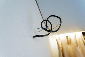 In the center of the room, there is a long black wire that is suspended and hanging down from the ceiling, which creates a very noticeable and interesting feature in the overall space photo