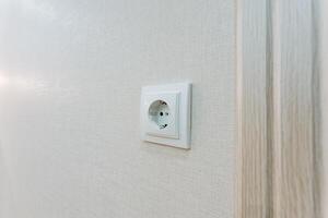 This is a detailed closeup photograph showing a white electrical outlet mounted securely on a wall, highlighting its design and functionality in relation to home electrical systems photo