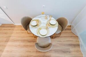 A beautiful round table adorned with plates and elegant glasses is set perfectly on top of a lovely wooden floor, making the interior design thoughtful and inviting for gatherings photo